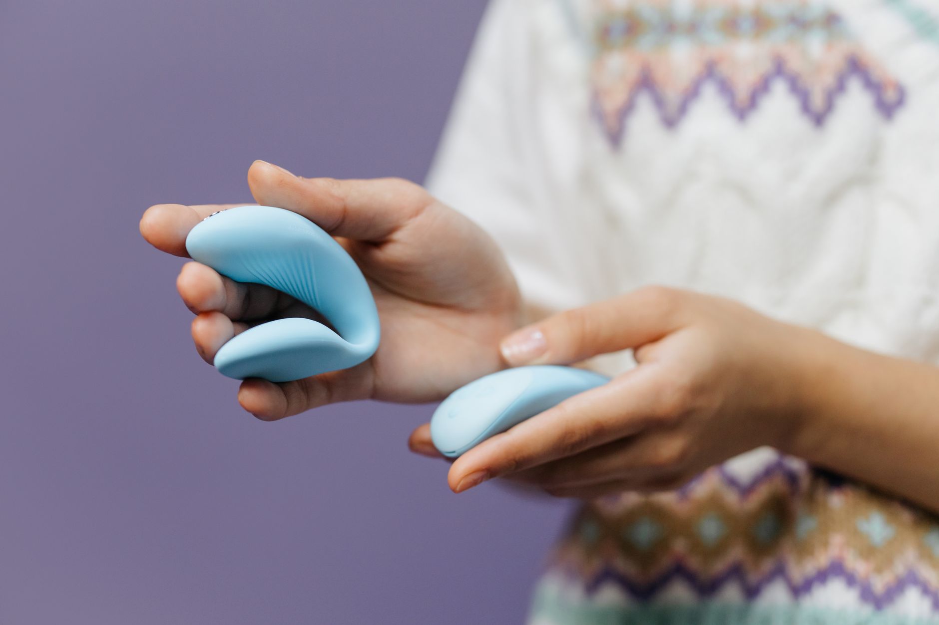Close-up of hands holding a sleek blue lemon vibrator against a purple background, symbolizing solo pleasure and personal reclamation.